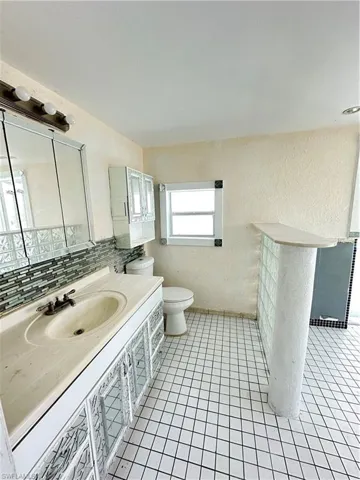 Bathroom with vanity, light tile patterned floors, and a textured wall