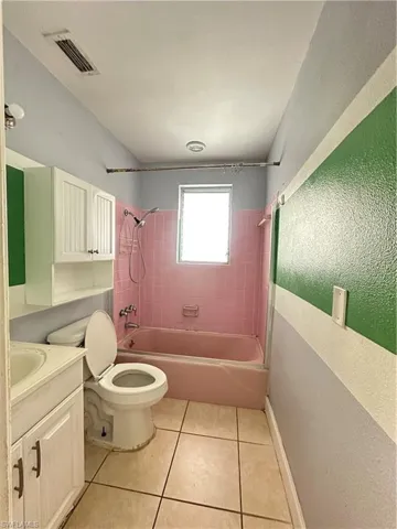Full bathroom with shower / tub combination, vanity, light tile patterned floors, and a textured wall