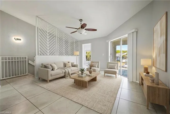 Spacious living area featuring large format tile flooring, a decorative half-wall with geometric cutouts, and a ceiling fan