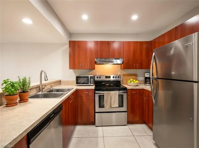 Kitchen featuring wood-finish cabinetry, stainless steel appliances, and a double basin sink
