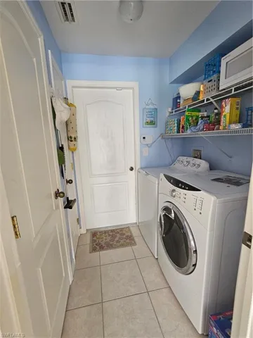 Laundry room featuring separate washer and dryer and light tile patterned flooring