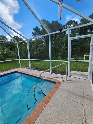 View of pool with glass enclosure and a patio area
