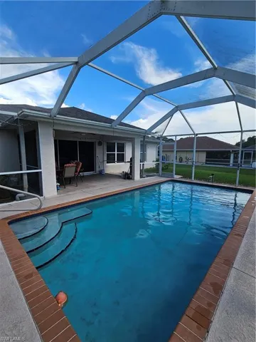View of swimming pool with glass enclosure and a patio area