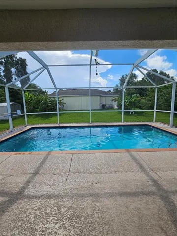View of swimming pool with glass enclosure, a yard, and a patio