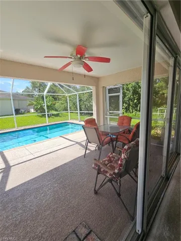 View of pool with ceiling fan, a patio, and glass enclosure