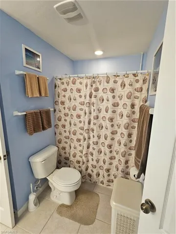 Bathroom with a shower with curtain, toilet, and tile patterned floors
