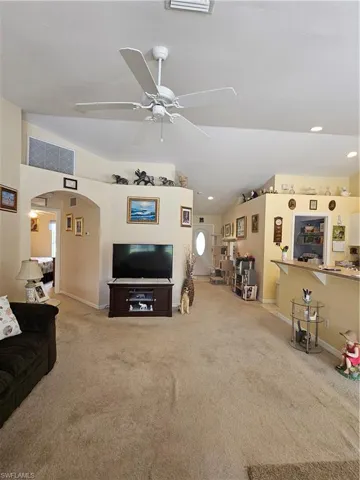 Living room with lofted ceiling, ceiling fan, and carpet