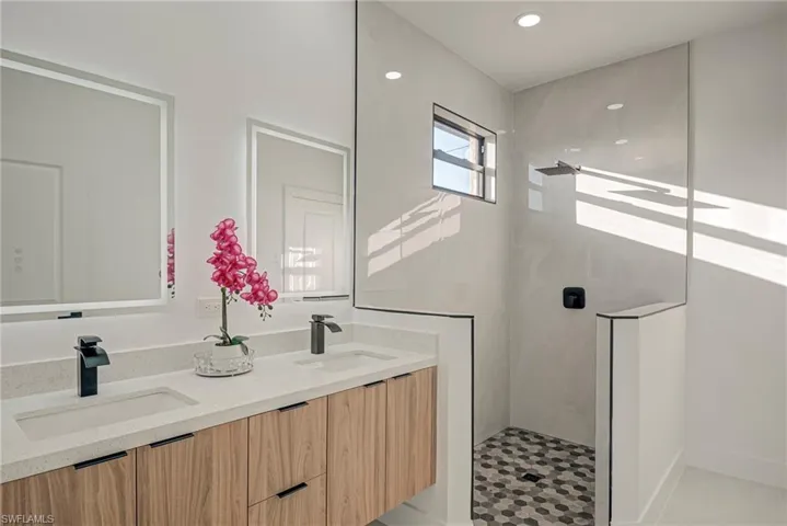 Bathroom featuring walk in shower, double vanity, and recessed lighting