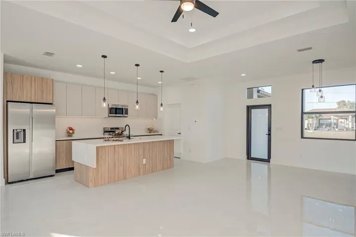Kitchen with stainless steel appliances, decorative light fixtures, a center island with sink, open floor plan, and recessed lighting