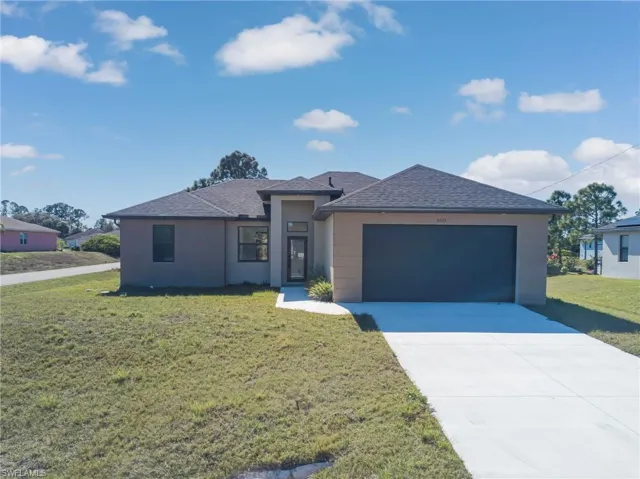 Prairie-style home featuring a front lawn, roof with shingles, driveway, and a garage