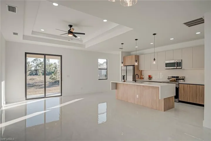 Kitchen featuring modern cabinets, a kitchen island with sink, pendant lighting, open floor plan, and recessed lighting
