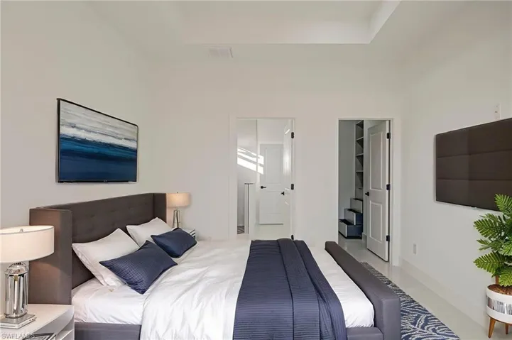 Bedroom featuring a spacious closet, ensuite bath, and a high ceiling