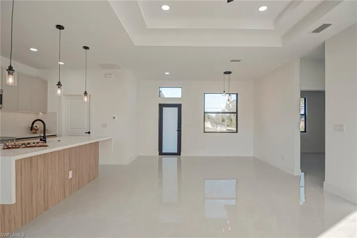 Kitchen featuring hanging light fixtures, recessed lighting, open floor plan, modern cabinets, and a kitchen island with sink