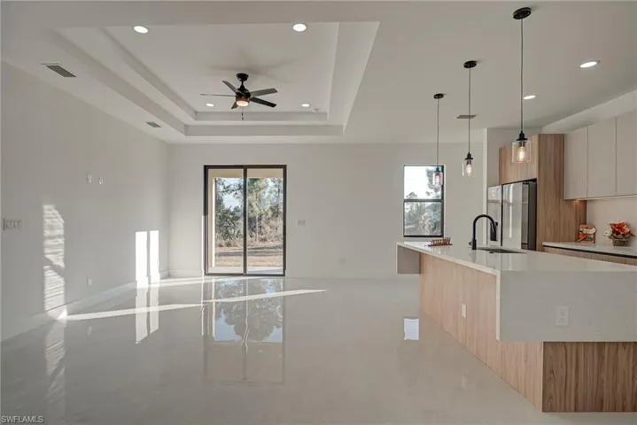 Kitchen featuring open floor plan, modern cabinets, pendant lighting, stainless steel refrigerator with ice dispenser, and recessed lighting
