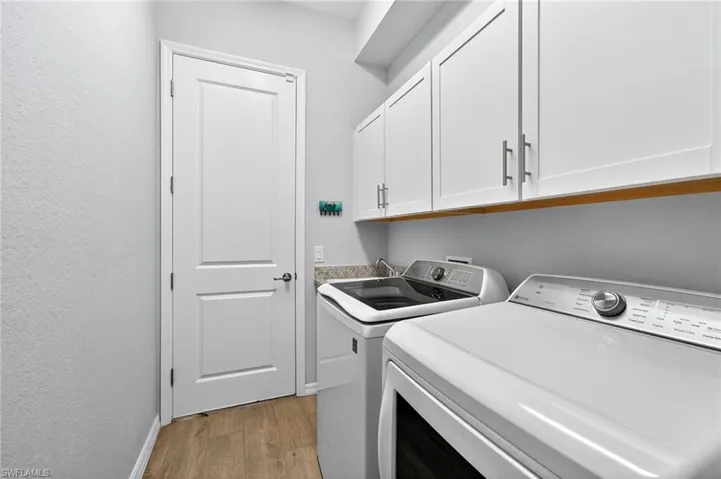 Laundry room with light wood finished floors, washing machine and dryer, and cabinet space