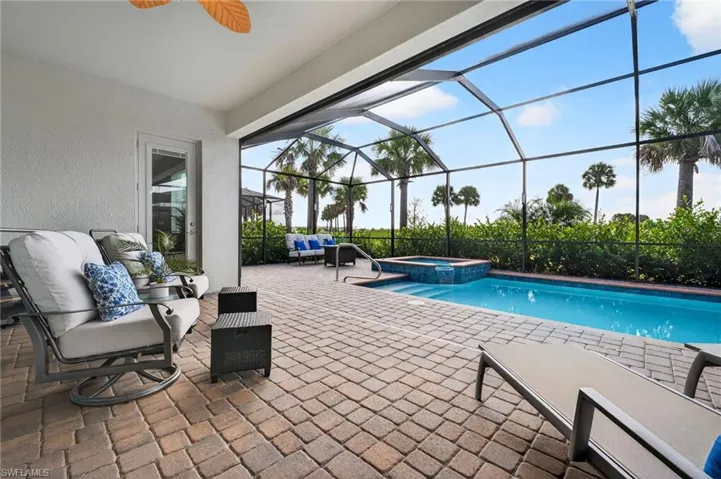 View of swimming pool featuring a patio, a sunroom, a pool with connected hot tub, glass enclosure, and outdoor lounge area