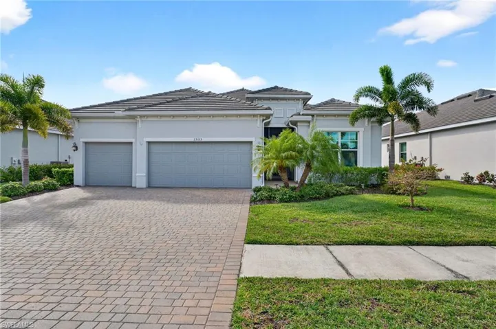 View of front of home featuring stucco siding, a front yard, decorative driveway, a garage, and a tiled roof
