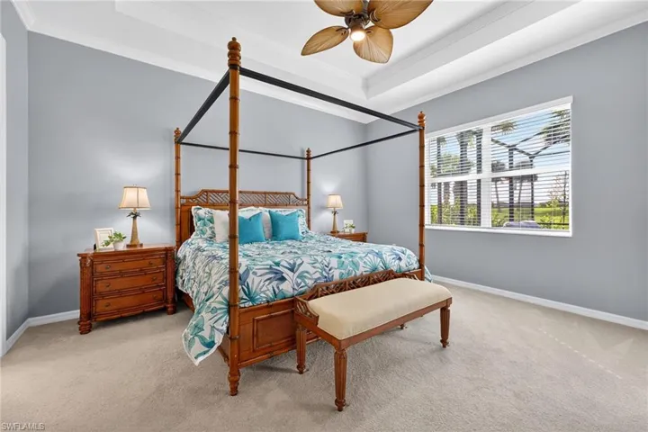 Bedroom featuring a raised ceiling, carpet floors, crown molding, and ceiling fan