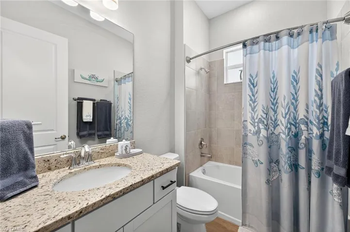 Bathroom featuring shower / bathtub combination with curtain, vanity, and a textured wall