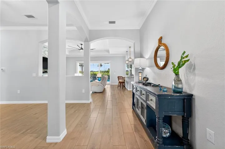 Entryway featuring a ceiling fan, arched walkways, ornamental molding, and light wood-style floors