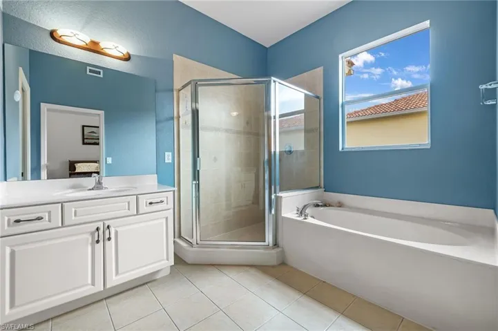 Bathroom with tile patterned floors, vanity, and plus walk in shower