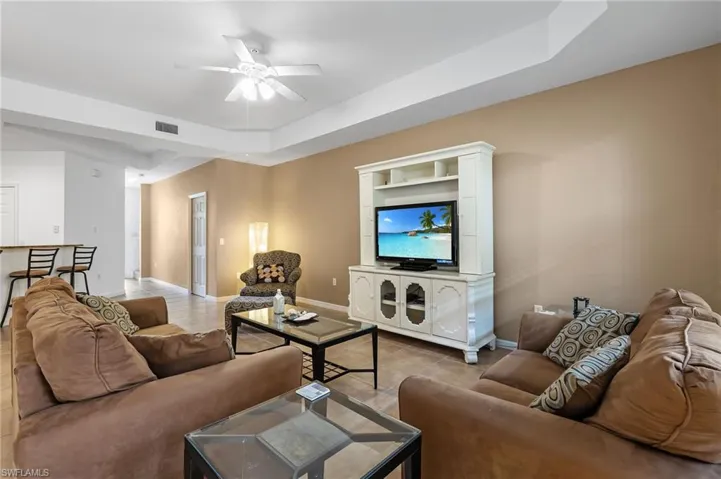 Living room featuring ceiling fan and a raised ceiling