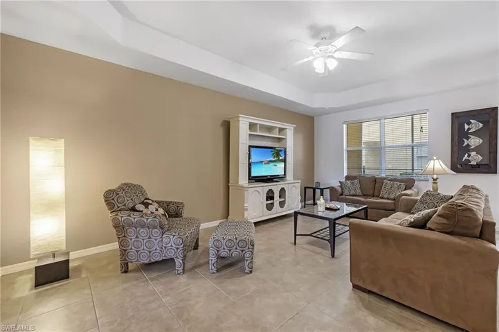 Tiled living room with a raised ceiling and ceiling fan