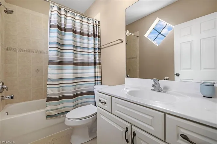 Full bathroom with tile patterned floors, shower / bath combo with shower curtain, vanity, and toilet