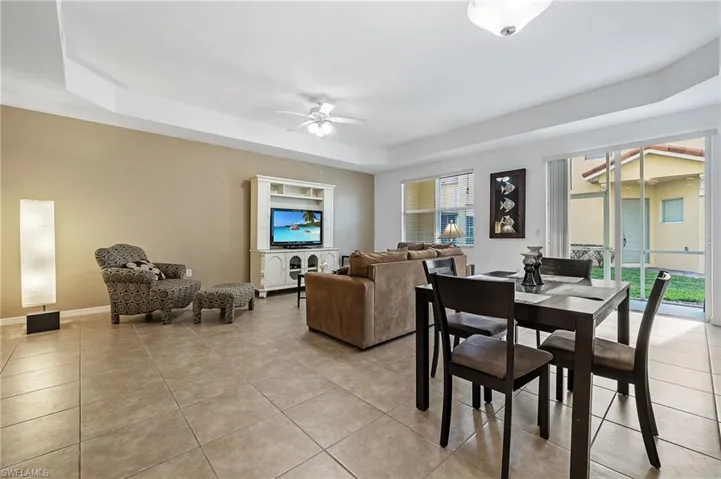 Tiled dining space with a tray ceiling and ceiling fan