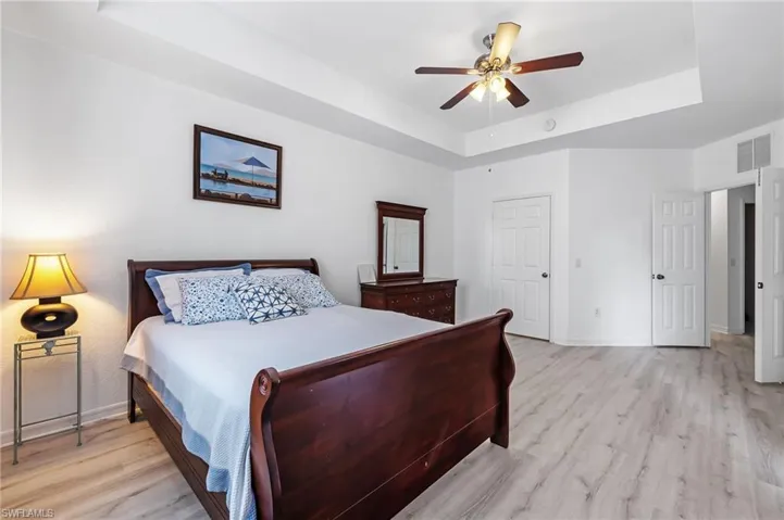 Bedroom featuring a raised ceiling, ceiling fan, and light hardwood / wood-style flooring