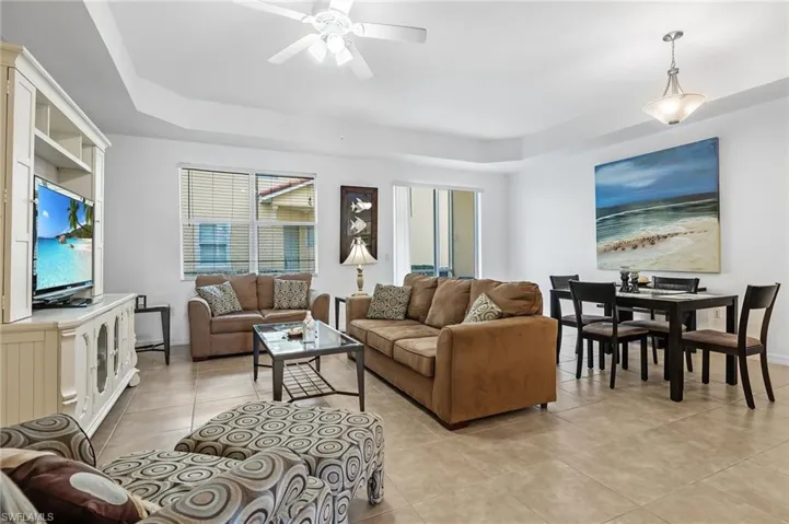 Tiled living room with a raised ceiling and ceiling fan