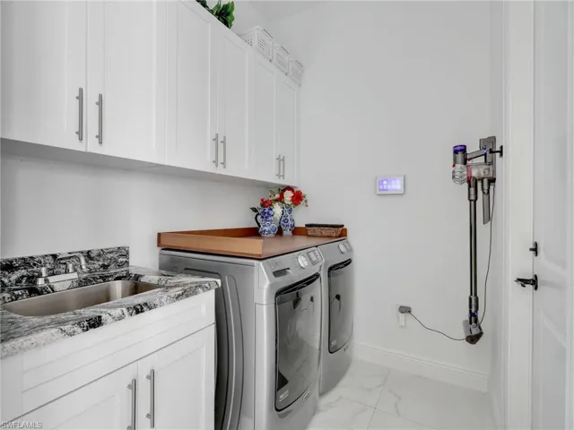 Laundry Room With White Shaker Cabinetry, Quartz Counter With Stainless Steel Sink , & Maytag Front Load Washer & Dryer