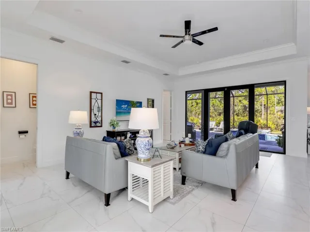 Living Room With Tray Ceiling , Ceiling Fan, Glass Doors Overlooking the Pool and Rear Yard, & Powder Room