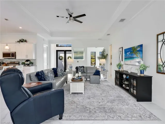 Living Room With Tray Ceiling and Ceiling Fan, Kitchen, & Front Entry With Transom Window