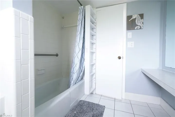 Bathroom with tile patterned flooring and shower / bath combo with shower curtain