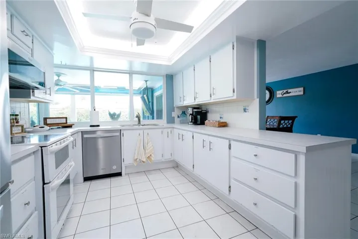 Kitchen with stainless steel appliances, a ceiling fan, backsplash, a peninsula, and a raised ceiling