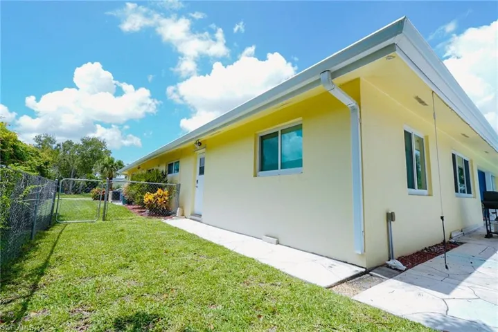 View of side of property featuring stucco siding, a gate, and a patio area