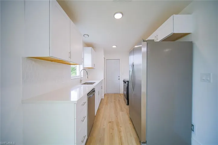 Kitchen featuring appliances with stainless steel finishes, light wood finished floors, white cabinetry, light countertops, and recessed lighting
