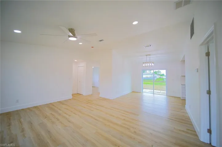 Empty room with light wood-style floors, a chandelier, a ceiling fan, and recessed lighting