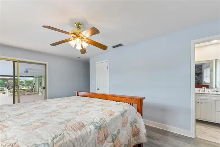 Bedroom with access to outside, sink, hardwood / wood-style flooring, ceiling fan, and connected bathroom