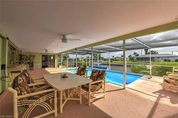 View of pool featuring a lanai, a patio area, ceiling fan, and a water view