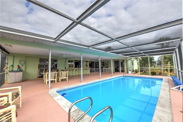 View of swimming pool with glass enclosure, ceiling fan, and a patio