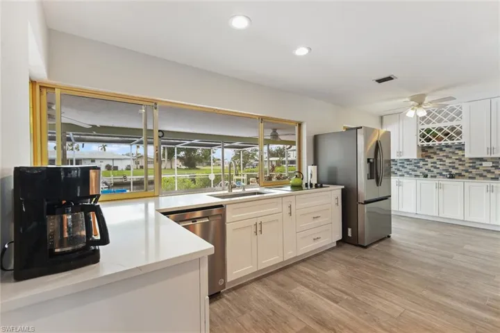 Kitchen featuring sink, tasteful backsplash, light hardwood / wood-style flooring, white cabinets, and appliances with stainless steel finishes