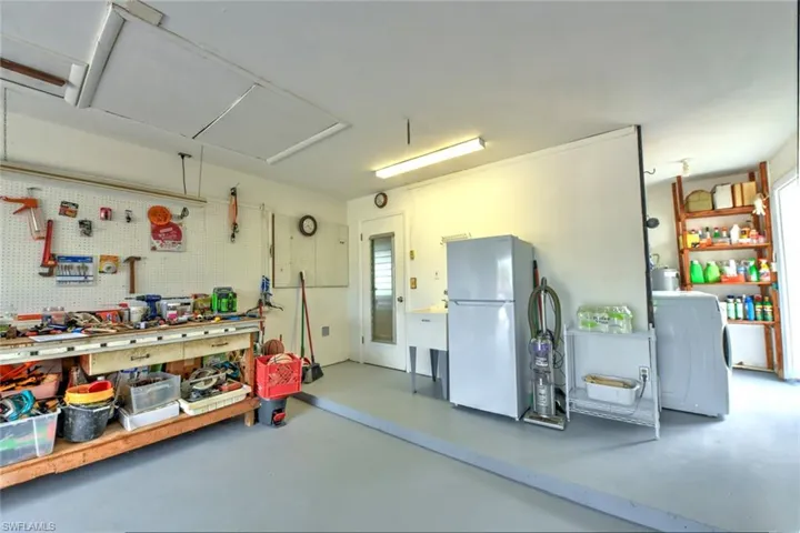 Garage with washer / dryer, a workshop area, and white refrigerator