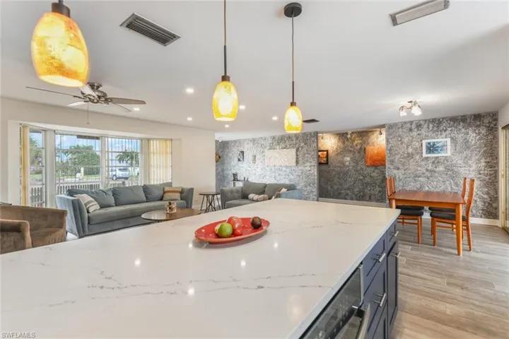 Kitchen featuring decorative light fixtures, light hardwood / wood-style floors, light stone counters, and ceiling fan