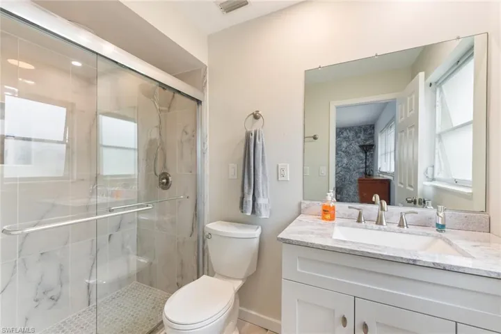 Bathroom with plenty of natural light, vanity, a shower with door, and toilet