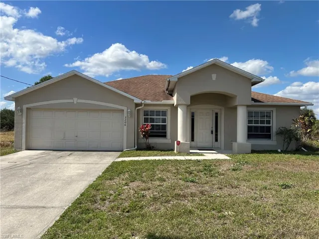 Ranch-style house featuring a garage and a front lawn