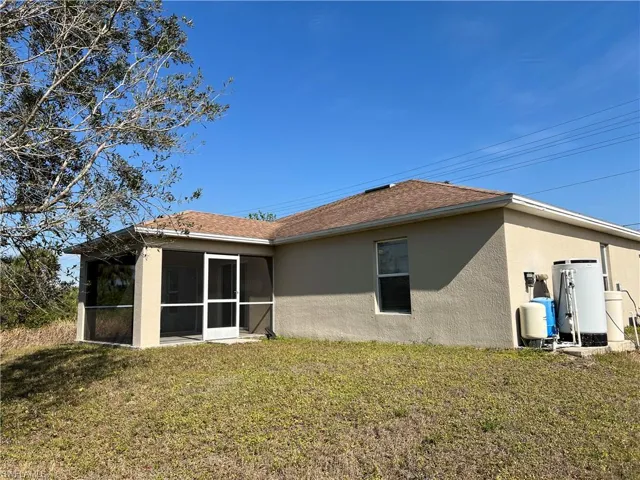 Rear view of house with a lawn and a lanai
