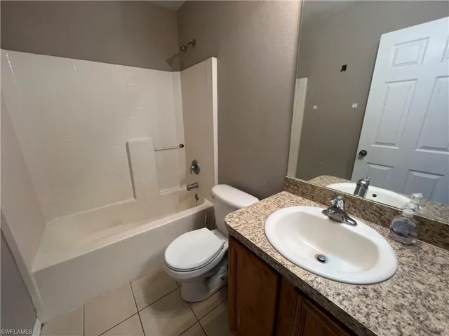 Full guest bathroom with vanity, tile patterned flooring,  shower combination, and toilet