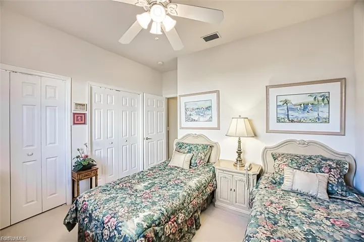 Bedroom with multiple closets, ceiling fan, and light carpet